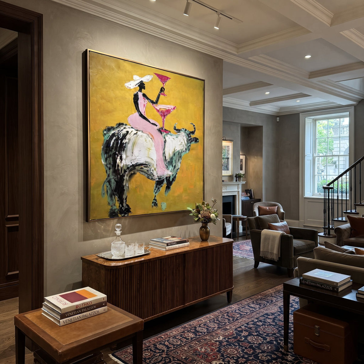 Pink Bull Martini Rider focuses on pink-clad cowgirl on grey bull lifting a martini against mustard ground. The composition is built from the exact pose, clothing shape, accessories, furniture, animal form, shoreline, palm shape, surfboard, or table arrangement visible in this artwork, so the image reads as a specific modern figurative painting rather than a generic decorative abstract. The pink; mustard; grey palette gives the piece its main atmosphere, while smaller dark and light accents